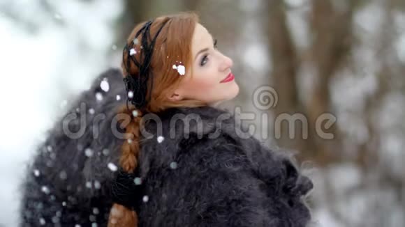 在森林里的一场冬天的大雪下戴着羽绒围巾的漂亮女孩视频的预览图