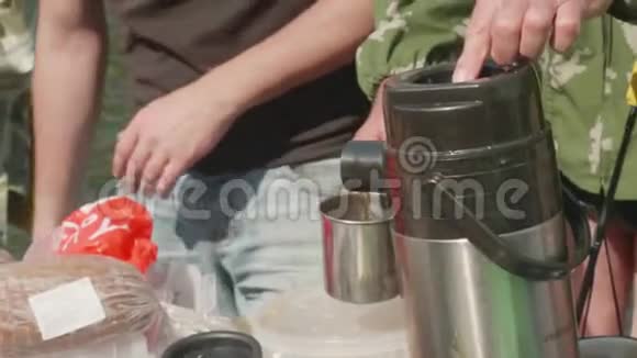 关闭视野人的手把热水瓶里的热茶倒在杯子里视频的预览图