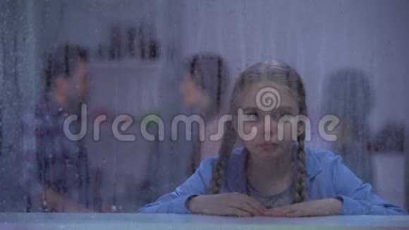 小女孩在雨窗后哭泣父母冲突家庭视频的预览图