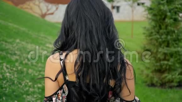 快乐微笑的黑发女郎从草地上的一个夏日公园里的镜头前跑开视频的预览图