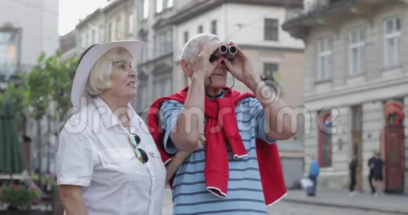 在市中心散步的老年男女游客用望远镜观看视频的预览图