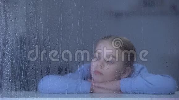 雨天躺在窗台上的孤独女孩梦想着回家的孤儿视频的预览图