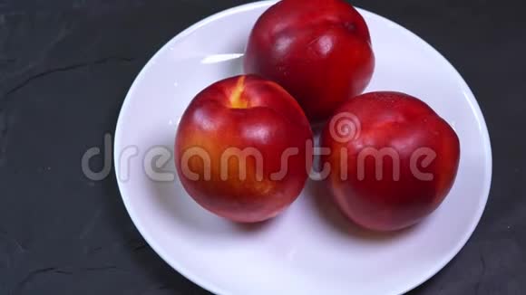 把三个鲜熟的红黄桃子放在盘子里视频的预览图