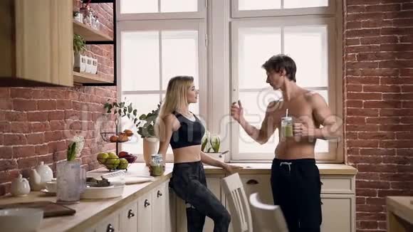 一对肌肉发达的年轻夫妇在锻炼后喝着健康的鸡尾酒谈笑风生视频的预览图