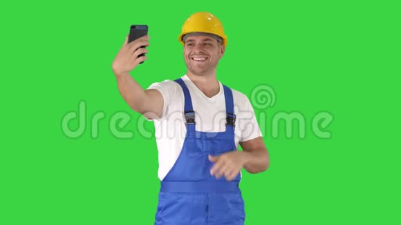 微笑英俊的年轻建筑工用手机在绿色屏幕上自拍色度键视频的预览图