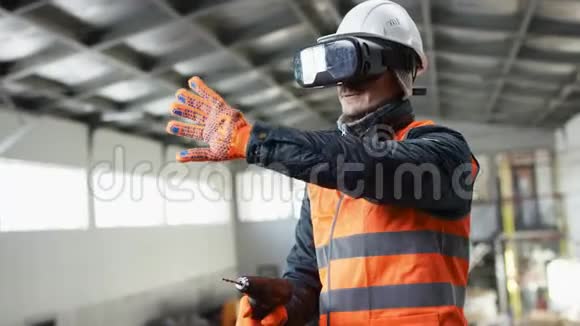 戴着安全帽穿着工作服的人的胡子和胡子正站在机库的中间用钻头虚拟视频的预览图