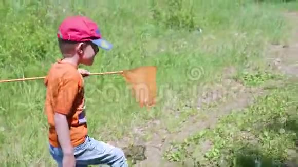 这个男孩钓到了一条小鱼那孩子带着一条鱼在森林小径上走美丽的夏日风景户外娱乐视频的预览图