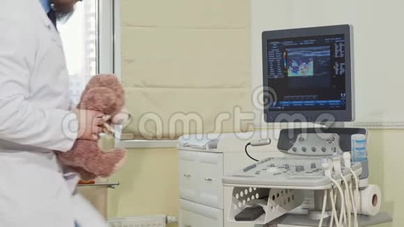 友好的男儿科医生拿着泰迪熊玩具对着镜头挥手视频的预览图