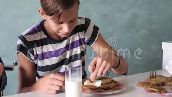 青少年吃牛奶和酸奶油煎饼视频的预览图