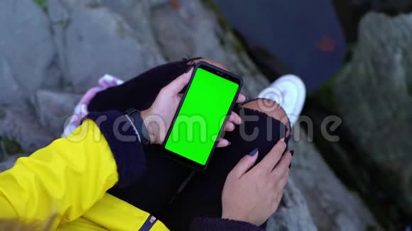 女孩使用智能手机与彩色绿色屏幕跟踪冰铜vfx准备附近的山河岩石石头自然视频的预览图