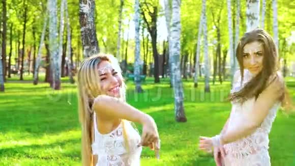 两位身着迷人服装和配饰的妇女在阳光明媚的桦树林里跳舞视频的预览图