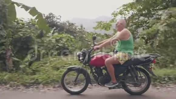 骑摩托车的人骑摩托车在青山上旅行驾驶热带高地摩托车的老人视频的预览图