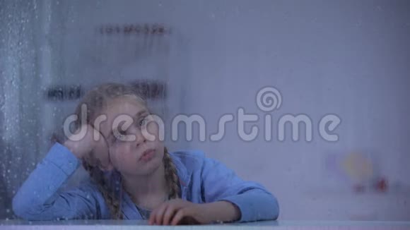 在下雨的窗户后面惹怒了小女孩养父母来收养孩子视频的预览图