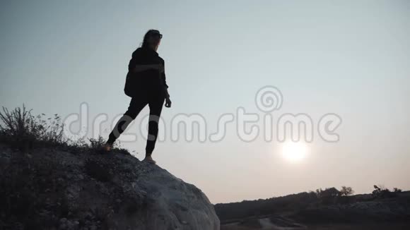 剪影年轻女孩带着背包从山顶欣赏日落日落时分的游客人民视频的预览图