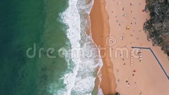 4普拉亚达阿德拉加海滩的空中稳定镜头白色大西洋海浪向沙滩翻滚游客络绎不绝视频的预览图