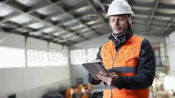 戴着安全帽穿着工作服的胡须和胡子正站在机库中间用他的工具检查视频的预览图
