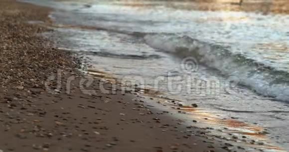 在沙滩上用许多小石头冲过的海浪特写视频的预览图