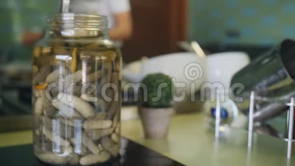 厨师在厨房工作前景玻璃罐里有腌黄瓜背景是在一个厨房里做饭视频的预览图