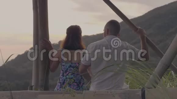 年轻男子拥抱美丽的女人坐在浪漫的约会在热带丘陵背景恋爱中的情侣视频的预览图
