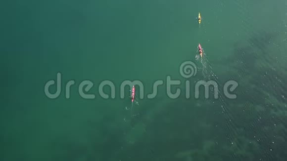 从高空向下浅水区的粉红色黄色和蓝色独木舟视频的预览图