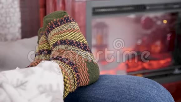 女人穿着温暖的羊毛袜子挨着燃烧的壁炉视频的预览图