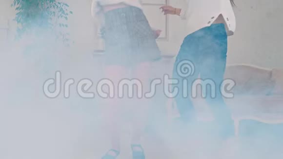 两个女孩在一个充满烟雾的明亮舒适的房间里跳舞和玩耍视频的预览图