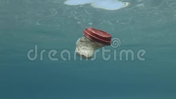 塑料污染一个带红色盖子的白色塑料杯漂浮在地中海蓝色的水面下视频的预览图