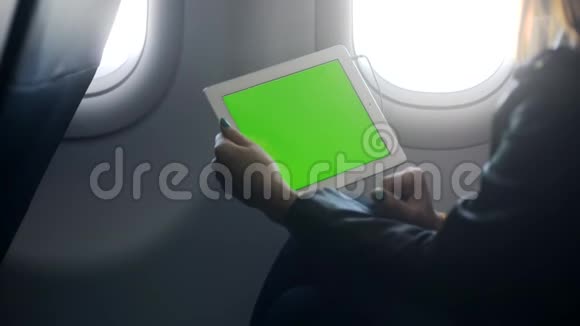 年轻女子坐在飞机上看着平板电脑上的媒体信息视频的预览图