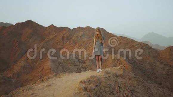 站在山顶上的年轻金发女人带日落的山景慢动作4k视频的预览图