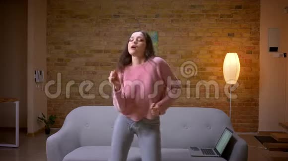 在室内一个舒适的公寓里年轻漂亮的黑发白种人女性在欢笑和欢乐中跳舞特写镜头视频的预览图