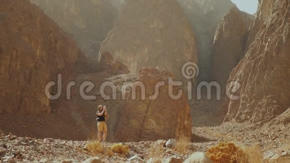 旅游女性沿着岩石峡谷散步在炎热的沙漠拍照沙漠峡谷背景埃及西奈慢视频的预览图