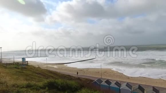 一段在沙滩上的暴风雨的慢镜头在沙滩上汹涌的海浪拍打着沙滩上的一条长廊下面是沙滩小屋视频的预览图