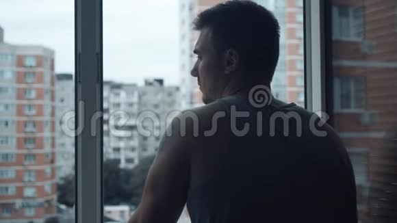 一个人站在敞开的窗户附近看着这座城市视频的预览图