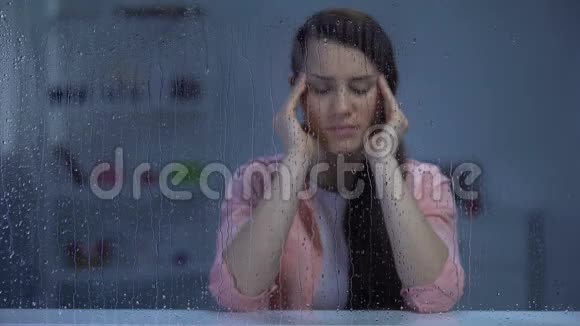精疲力竭的妇女在雨窗后头痛偏头痛视频的预览图