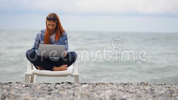在海边使用现代笔记本电脑的漂亮女人视频的预览图