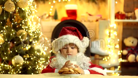 圣诞快乐戴着圣诞帽的圣诞小男孩圣诞节的食物和饮料快乐的孩子圣诞老人可爱的男孩在吃视频的预览图