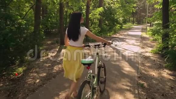 女人骑着自行车走在公园里视频的预览图