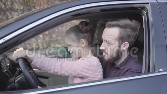 特写肖像的父女双手坐在豪车轮后父亲教女孩视频的预览图