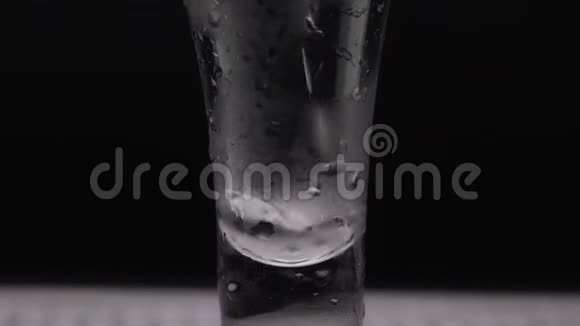 在黑色背景下将一瓶伏特加倒入玻璃杯中倒酒喝伏特加龙舌兰关闭视频的预览图