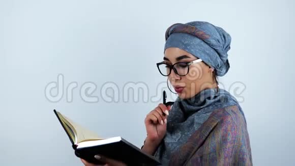年轻漂亮的阿拉伯商务女性戴着眼镜在笔记本上找到了必要的信息接触到她的脸视频的预览图