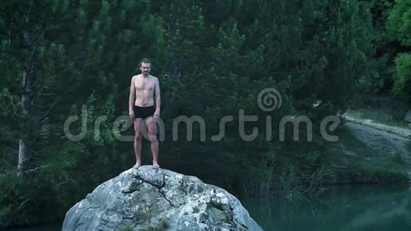 暑假或度假的年轻人从山林湖中央的石头上跳下来跳跃到视频的预览图