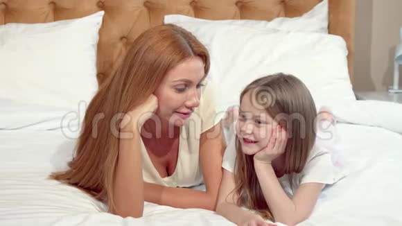 母女俩对着镜头微笑一起躺在床上视频的预览图