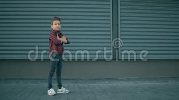 可爱时尚的模特男孩正在摆姿势时尚严肃的小男孩正看着现代蓝墙背景的镜头视频的预览图