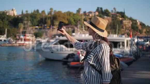 穿着休闲装背包在游艇码头自拍的千禧时髦女游客视频的预览图