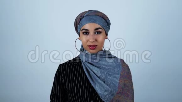年轻美丽的阿拉伯女人微笑着把无线耳机放在她的耳朵上放在孤立的白色背景上视频的预览图