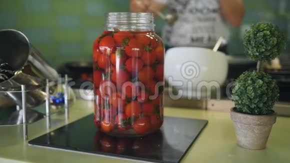 厨师在厨房工作在前景玻璃罐中有腌制的西红柿在背景中烹饪厨师视频的预览图