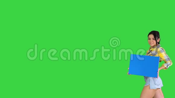 年轻迷人的黑发模特拿着空板在绿色屏幕蓝色模型视频的预览图