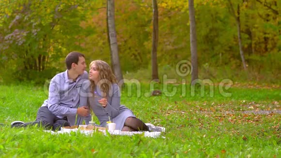 一个男人亲吻公园里草坪上的一个女人视频的预览图