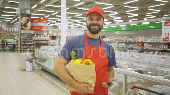 穿着红色制服的帅哥站在超市里手里拿着纸袋微笑视频的预览图