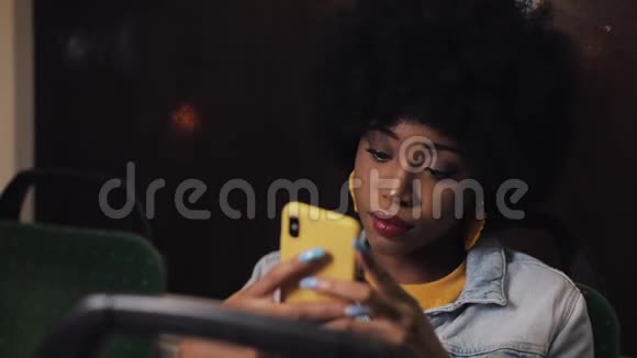 可悲的非裔美国妇女在公共交通工具上使用智能手机晚上视频的预览图
